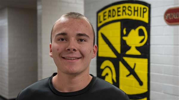  JROTC Cadet Dakota Huggard stands in front of military insignia.
