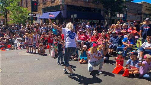 Assistant Superintendent Mary Kay Walton high fives children in the crowd at the 4th of July parade. 
